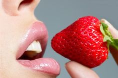 a close up of a person eating a strawberry