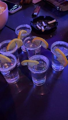 several shot glasses with lemon wedges sit on a table