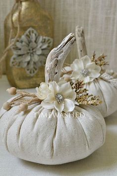 two white pumpkins with flowers on them sitting next to a gold vase and other decorative items