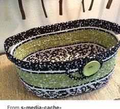 a green and white basket sitting on top of a wooden table