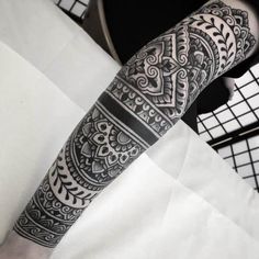 a man's arm with an intricate tattoo design on the forearm and hand, in black and white