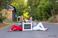 two women sitting on the road with a sign