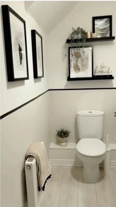 a white toilet sitting in a bathroom next to a radiator and pictures on the wall