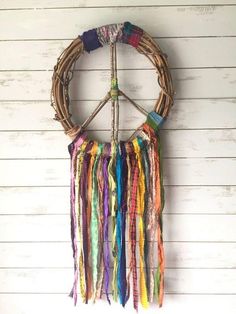 a peace sign made out of multicolored ribbons hanging on a wall with white planks