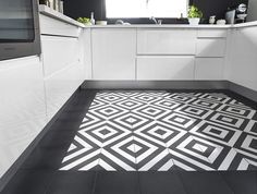 a kitchen with black and white flooring in the center, an area rug that looks like a maze