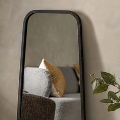 a mirror sitting on top of a wall next to a couch