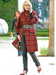 a woman talking on a cell phone while wearing a plaid coat and high heeled shoes