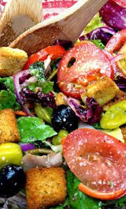 a salad with croutons, tomatoes, lettuce and olives