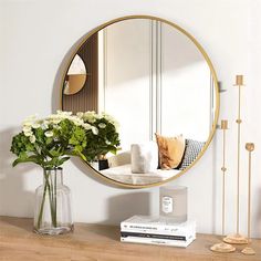 a mirror sitting on top of a wooden table next to a vase filled with flowers