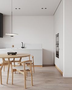 a table and chairs in a room with white walls, wood floors and flooring