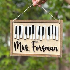 a hand holding a sign that says, mrs fersman with piano keys on it