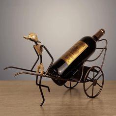 a wine bottle holder with a man pushing a horse drawn carriage holding a golden hat