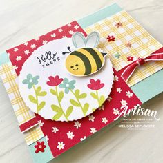 a close up of a card with a bee on it and flowers in the background