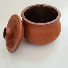 a brown vase sitting on top of a white table next to a black container with a lid