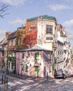 an old pink building with green shutters on the side and cars parked in front