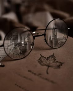 a pair of glasses sitting on top of an open book with a leaf drawn on it