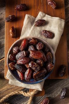 a bowl full of raisins sitting on top of a wooden table next to a cloth