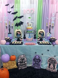 a table topped with lots of halloween decorations and desserts covered in frosting on top of it