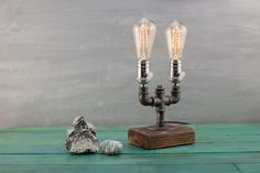 two light bulbs sitting on top of a wooden table next to a rock and lamp