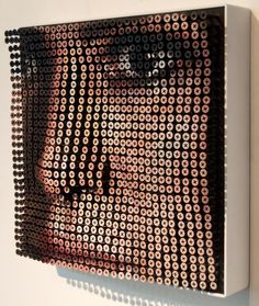 an art piece made out of small circles on a white wall with a man's face in the middle