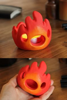 a hand holding an orange toy with flames coming out of it's mouth and inside