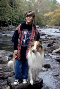 a man standing next to a dog on top of a rock