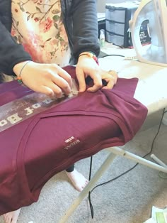 a woman is cutting fabric on top of a chair