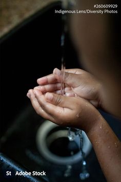 a person washing their hands in a sink with water coming from the faucet