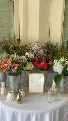 there are many flowers in buckets on the table