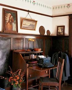 an old fashioned desk and chair in a room with pictures on the wall above it