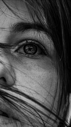 a black and white photo of a woman's face with her hair blowing in the wind