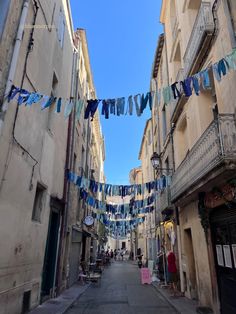 there are many people walking down the street in front of buildings with flags hanging from them