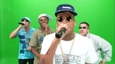 a group of men standing next to each other in front of a green screen holding microphones