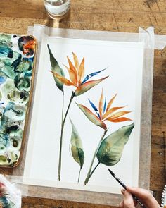 a person is painting flowers with watercolors on paper