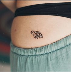 a woman's stomach with a small turtle tattoo on the side of her belly