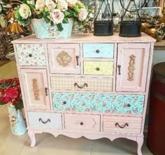 a pink dresser with flowers on top and other items in the back ground behind it