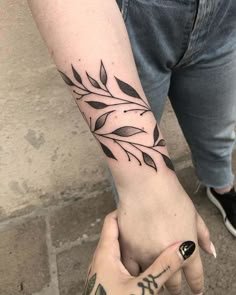 a person with a tattoo on their arm holding the hand of another person's wrist