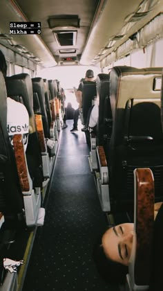 the inside of an airplane with people sleeping on seats and one person walking down the aisle