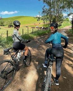 two people riding bikes on a dirt road