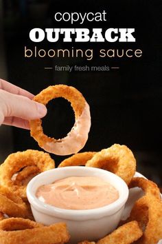 a person dipping something into a bowl of dip with onion rings on the side and text overlay that reads, copy outback blooming sauce family fresh meals