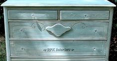 an antique dresser painted in silver with writing on it