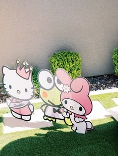 two hello kitty cutouts are standing in the grass