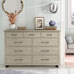 a bedroom with a dresser, mirror and pictures on the wall next to a couch