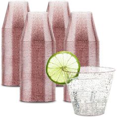 a group of pink vases and a glass with a lime slice