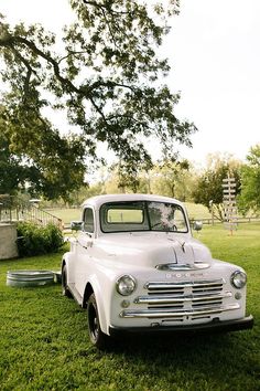 an old white truck is parked in the grass