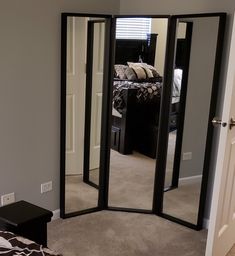 a room with a bed, mirror and black furniture in the corner on the floor