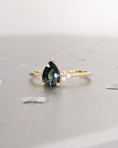 a green and white diamond ring sitting on top of a table