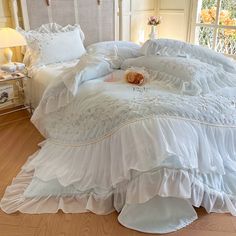 a white bed with ruffled bedspread and pillows