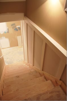 an empty room with wooden stairs leading up to the door and light fixture on the wall