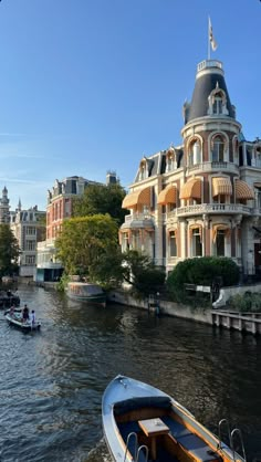 two boats are on the water in front of a large building with a turret roof